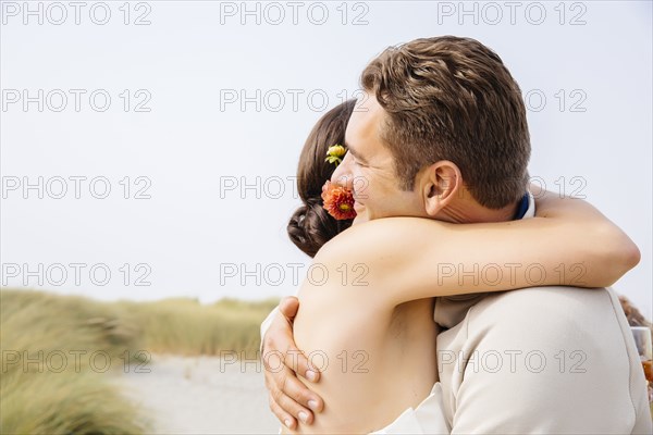 Caucasian bride and groom hugging in outdoor wedding