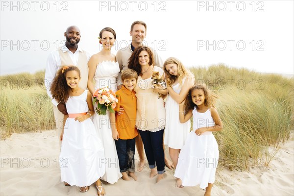 Bride and groom smiling with family at wedding