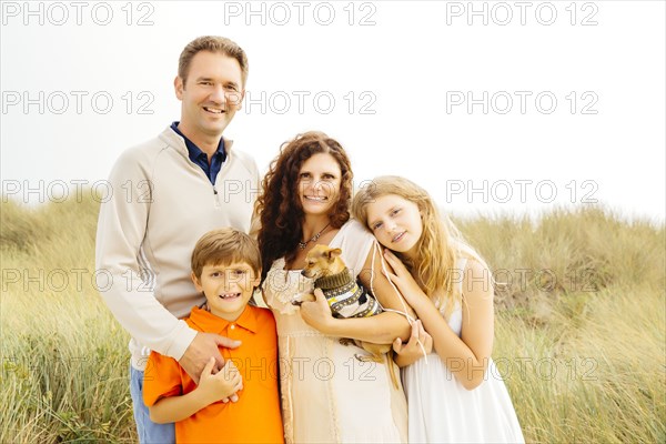 Family smiling with dog on beach