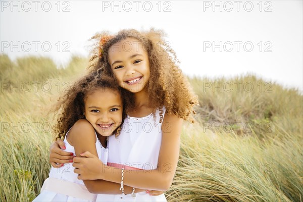 Mixed race sisters hugging outdoors