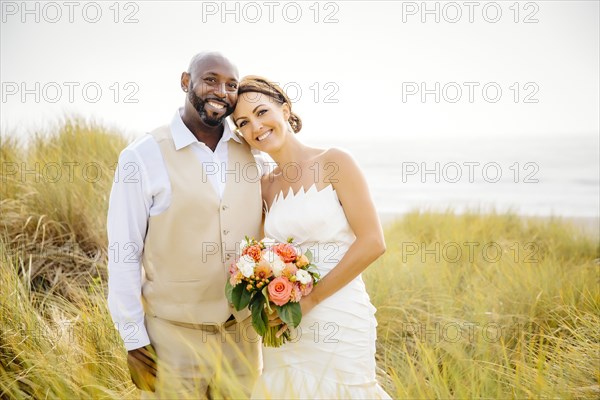 Newlywed couple smiling in grass