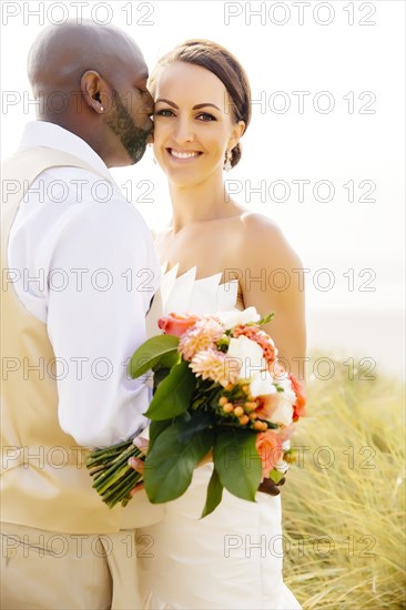 Newlywed couple kissing in grass