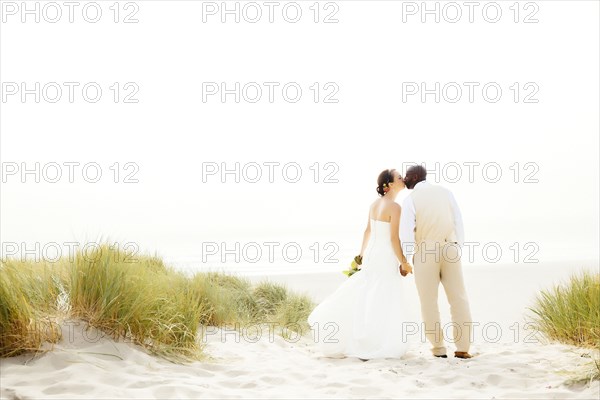 Newlywed couple kissing on beach