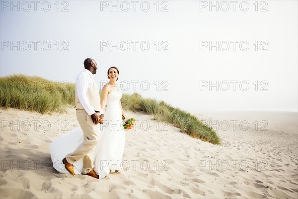 Newlywed couple walking on beach