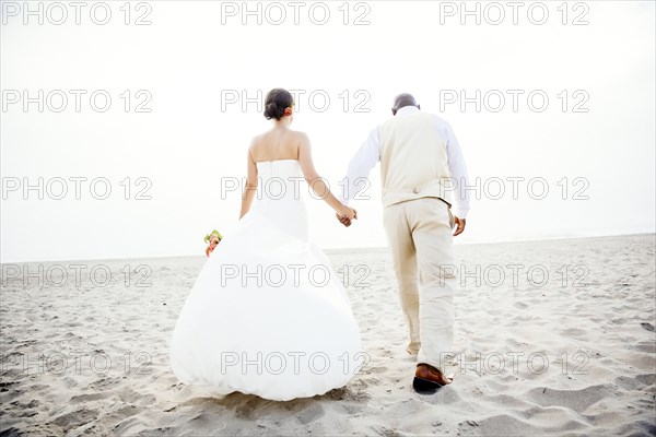 Newlywed couple walking on beach