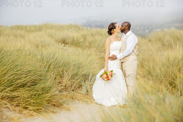 Newlywed couple kissing on beach