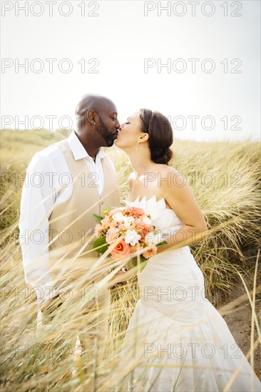 Newlywed couple kissing in grass