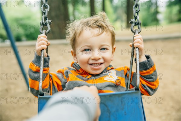 Caucasian mother pushing son on swing