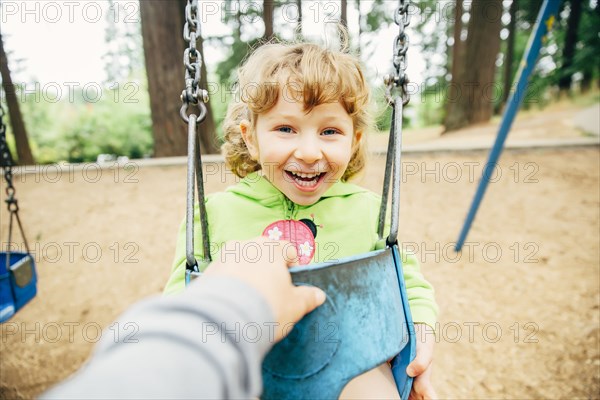 Caucasian mother pushing daughter on swing