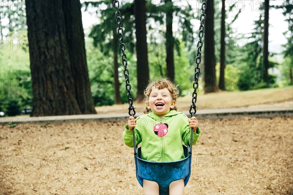 Caucasian girl playing on swing