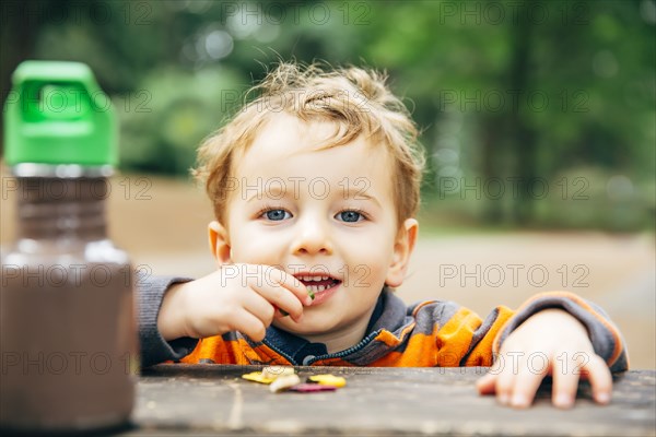 Caucasian boy eating snack at picnic table