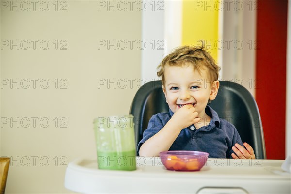 Caucasian boy eating in high chair