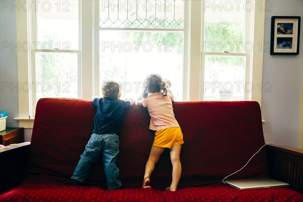 Caucasian children standing on sofa