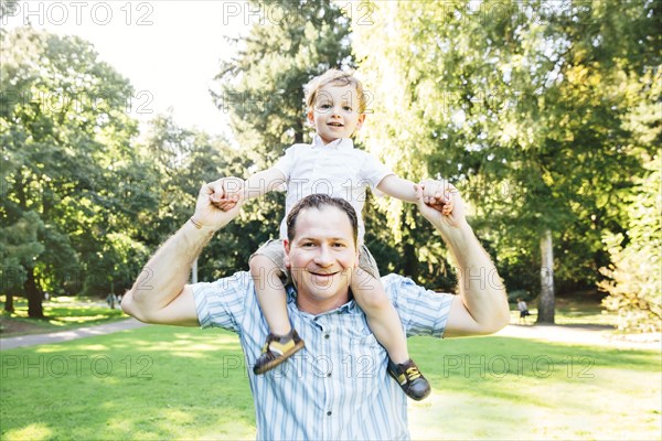 Caucasian father carrying son in park