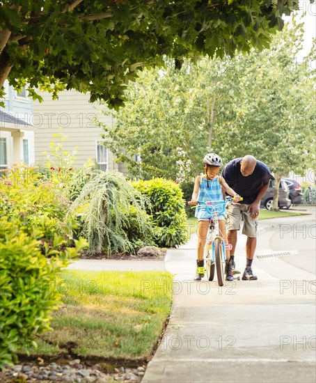 Father teaching daughter to ride bicycle