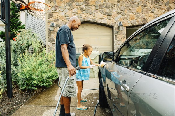 Father and daughter washing car