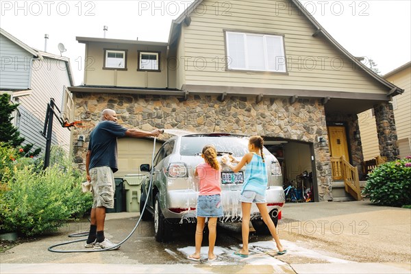 Father and daughters washing car