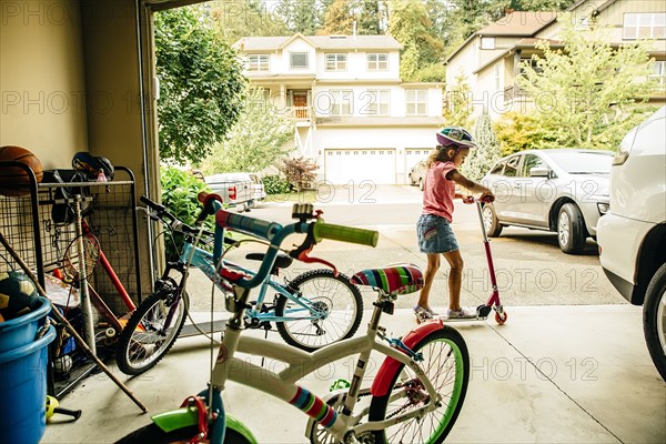 Mixed race girl playing with scooter