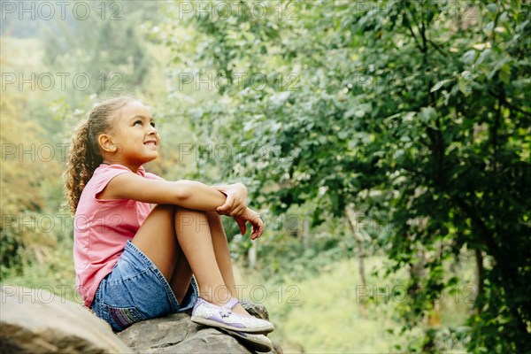 Mixed race girl sitting outdoors