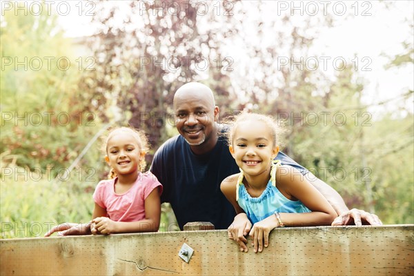 Father and daughters smiling outdoors