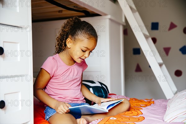 Mixed race girl reading on bed