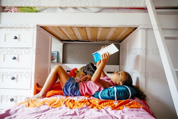 Mixed race girl reading on bed