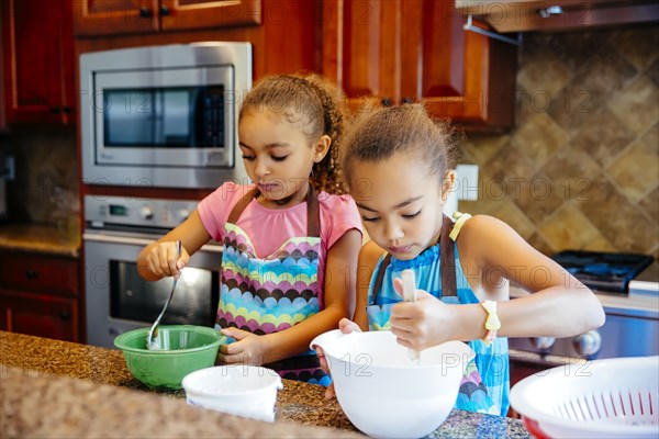 Mixed race sisters cooking in kitchen