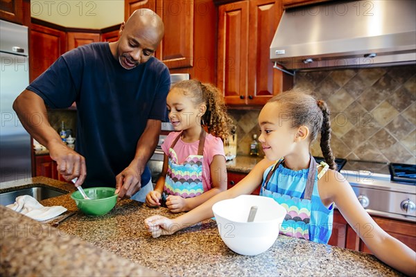 Father and daughters cooking in kitchen