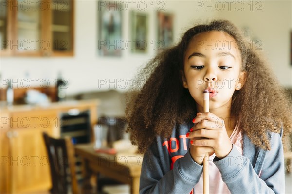 Mixed race girl blowing on pool cue