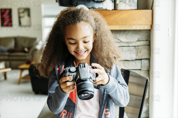 Mixed race girl using camera in living room