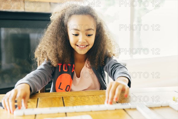 Mixed race girl playing with dominoes