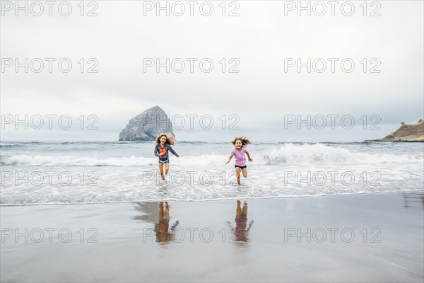 Mixed race sisters running on beach