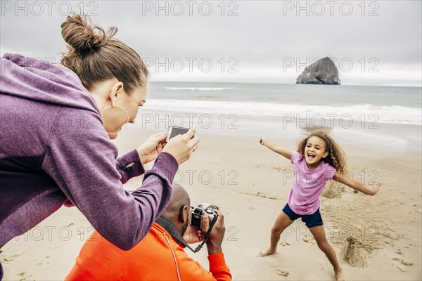 Parents photographing daughter on beach