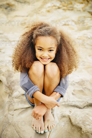 Mixed race girl hugging her knees