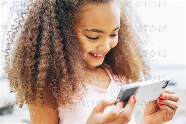 Mixed race girl using cell phone on beach