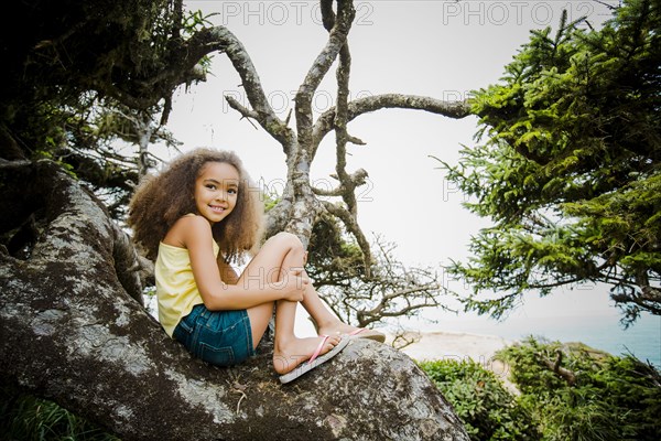 Mixed race girl smiling on rock