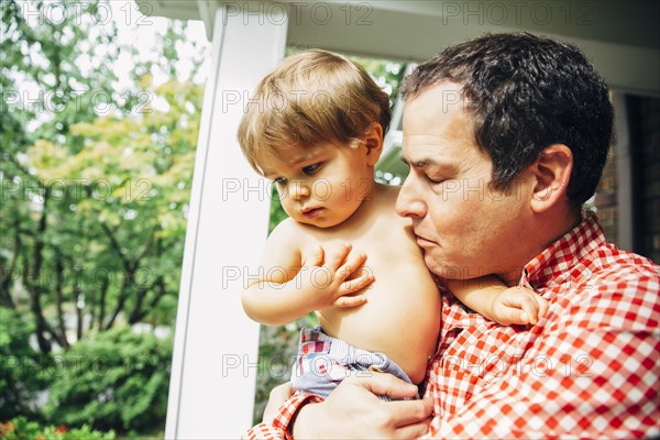 Father holding son on porch