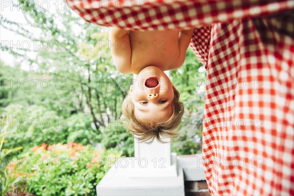 Baby boy hanging upside down outdoors