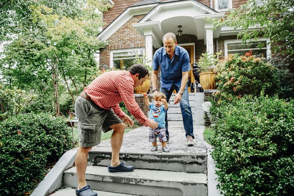 Gay fathers and baby son on steps