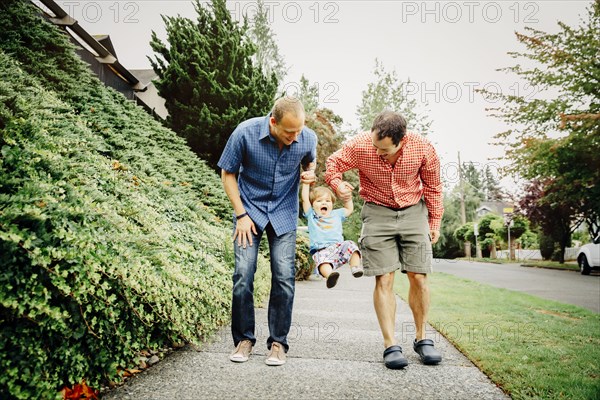 Gay fathers playing with baby son on sidewalk