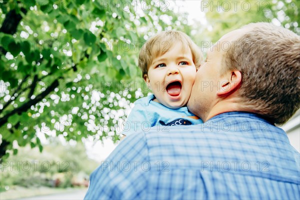 Father kissing cheek of baby son outdoors