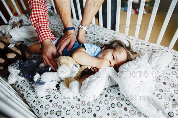 Gay fathers tickling baby son in crib