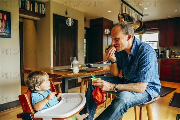 Father feeding baby son in high chair