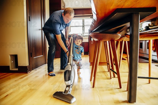 Father and son vacuuming kitchen