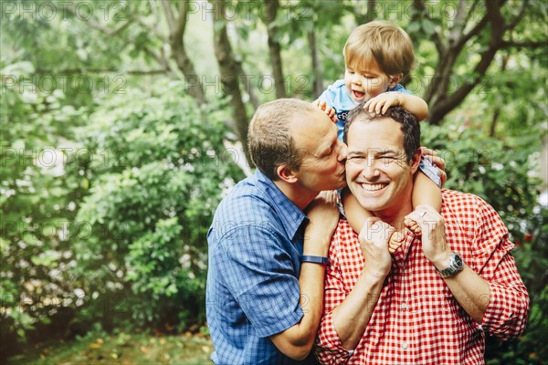 Gay fathers holding baby son outdoors