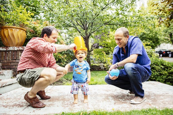 Gay fathers playing with baby son outdoors