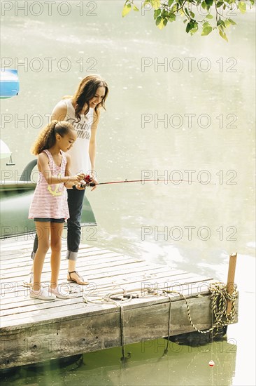 Mother and daughter fishing in lake