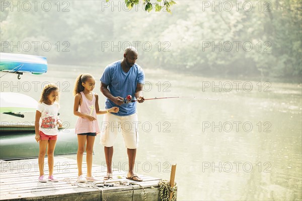 Father and daughters fishing in lake