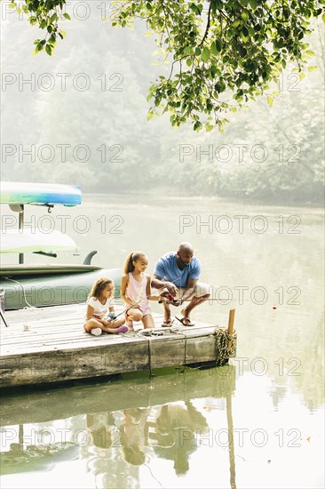 Father and daughters fishing in lake