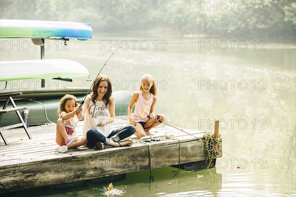 Mother and daughters fishing in lake